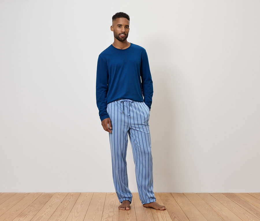 Mann trägt blauen Langarmpyjama und gestreifte Hose.