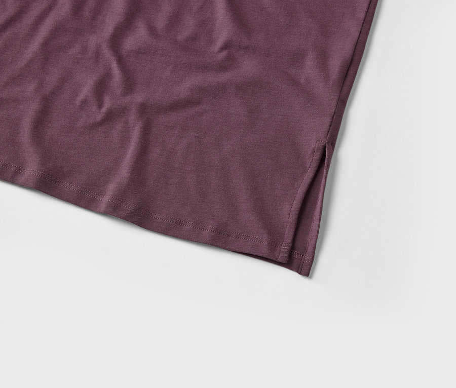 Detailaufnahme eines violetten T-Shirts mit Schlitz am unteren Saum.