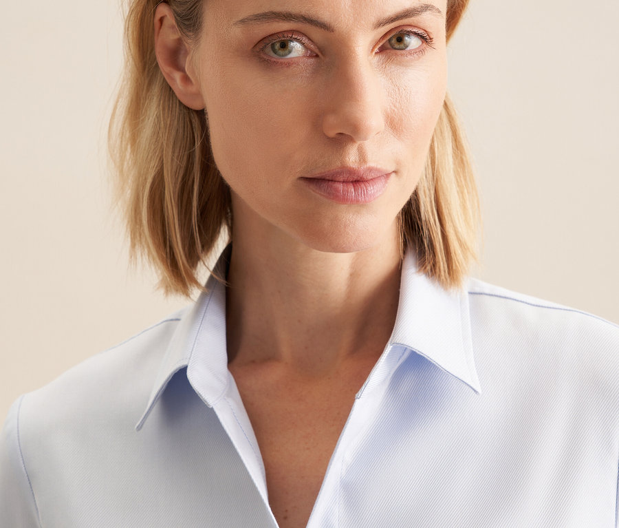 Porträt einer blonden Frau in hellblauer Seidensticker Twillbluse.