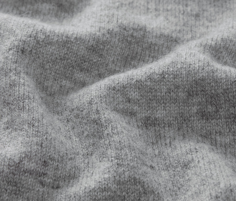 Nahaufnahme der Textur eines grauen Strickstoffs.