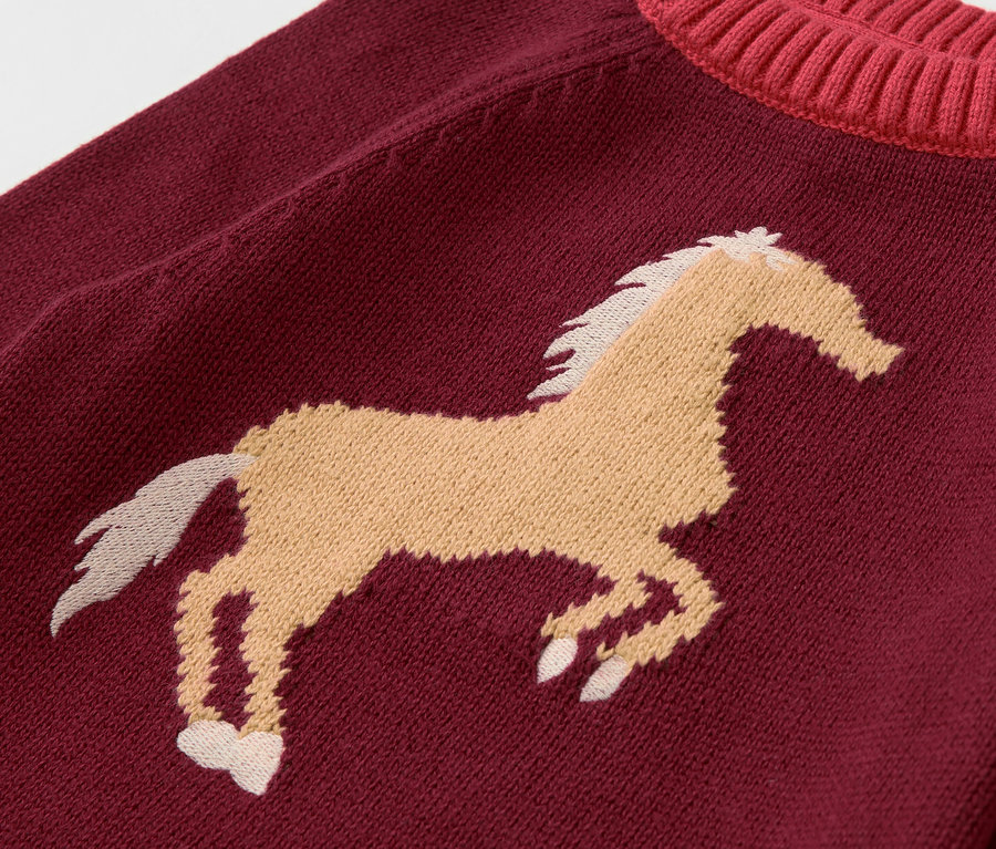 Detailansicht eines bordeauxroten Kinder-Strickpullovers mit braunem Pferdemotiv.