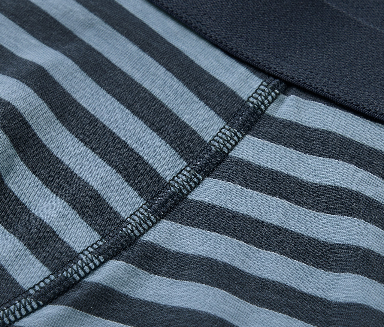 Detailansicht einer blau-grau gestreiften Boxershorts mit dunkelblauem Bund.