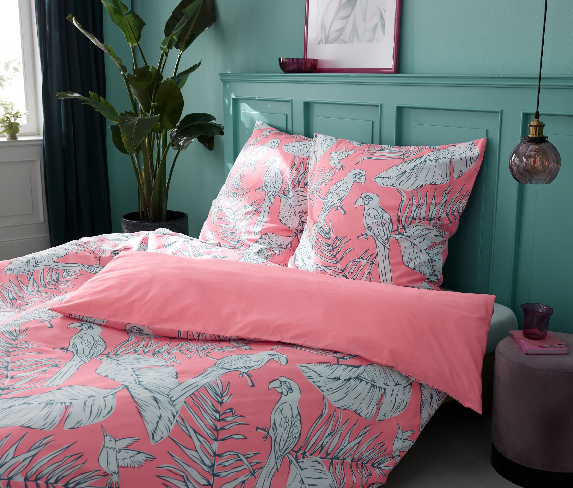 Vier Renforcé-Bettwäsche-Sets Tropical Rose in verschiedenen Größen auf einem Bett.