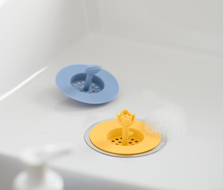 Im Waschbecken liegen zwei Abflusssiebe aus Silikon, ein blaues und ein gelbes.