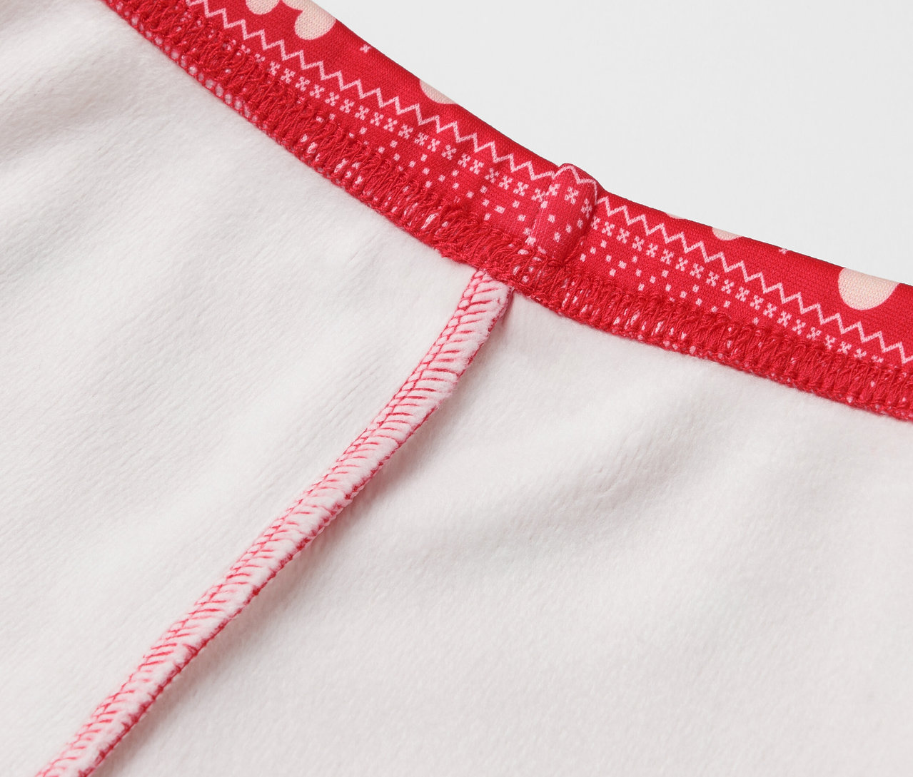 Detail eines weißen Kleidungsstücks mit rotem Rand und weißen Punkten.