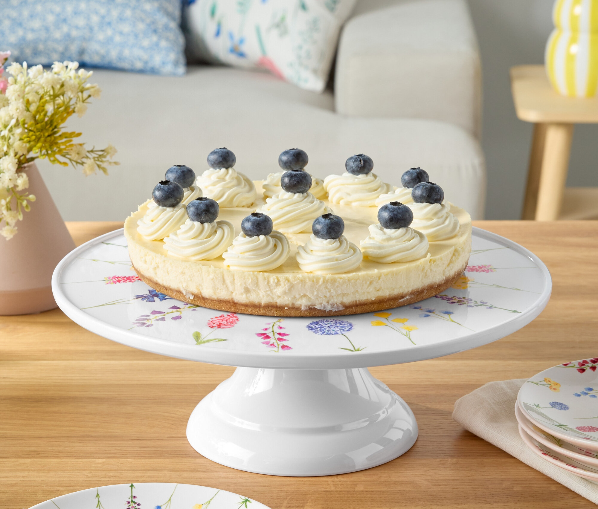 Kuchen mit Blaubeeren auf weißem Teller mit Blumenmuster.