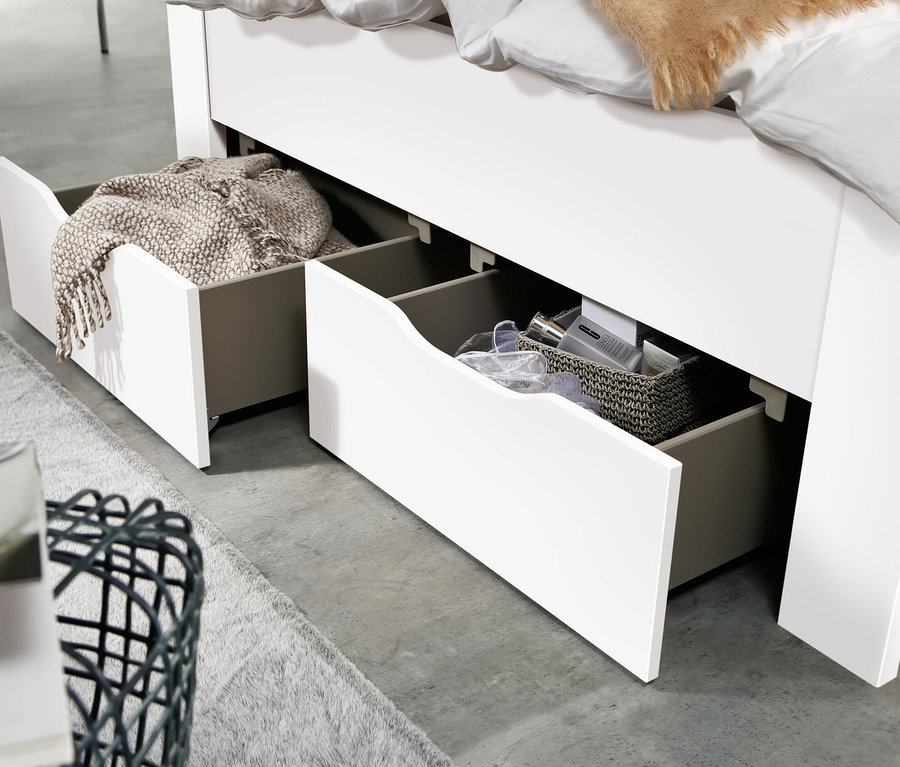 Detail eines weißen rauch Bett »Aditio Beds«, 140 cm, mit offenen Schubladen. In einer Schublade liegt eine Decke, in der anderen Kosmetik.