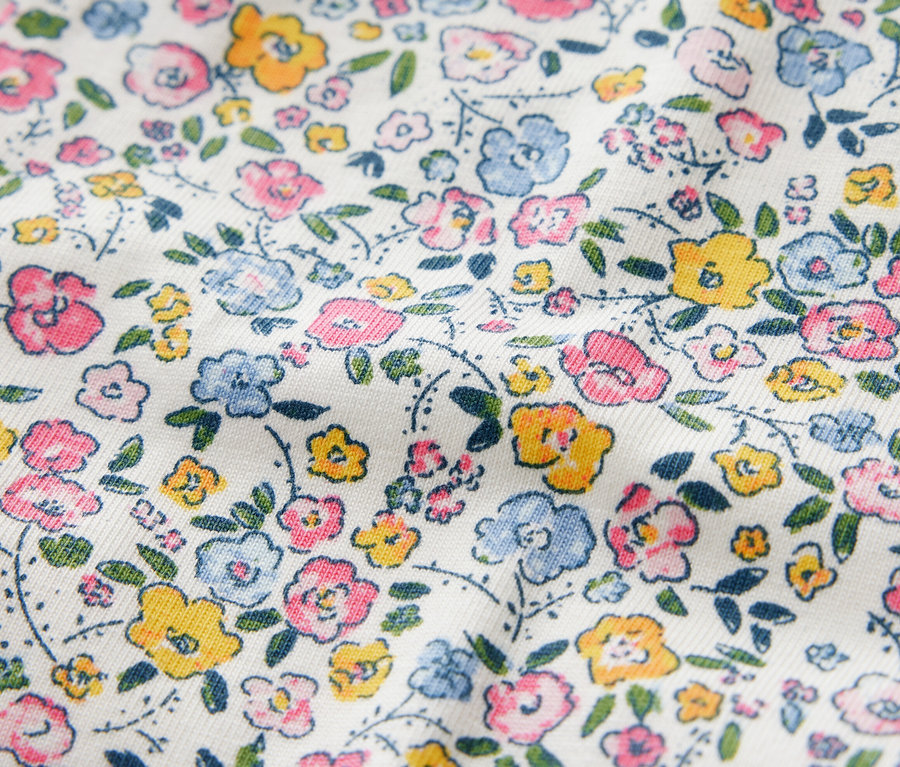 Detailaufnahme von Kinderleggings mit Blumenmuster in Rosa-, Blau- und Gelbtönen.