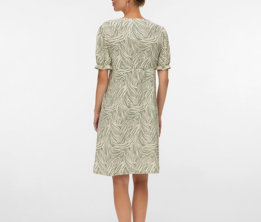 Frau von hinten, die ein knielanges Kleid mit Zebramuster und Sandalen trägt.