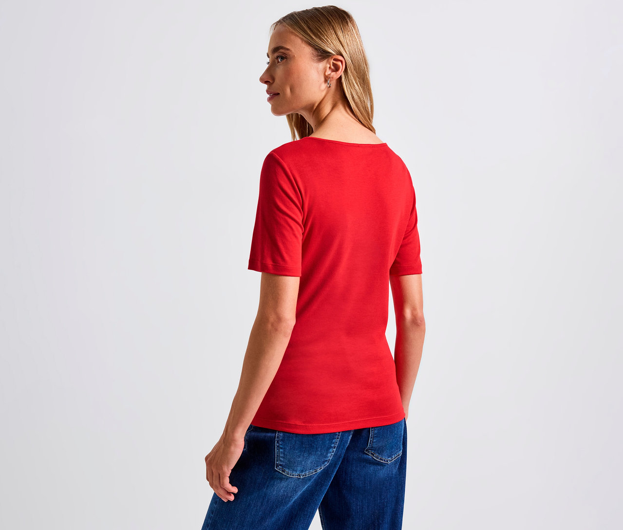 Frau trägt ein rotes Street One Shirt mit Herzausschnitt und Jeans.