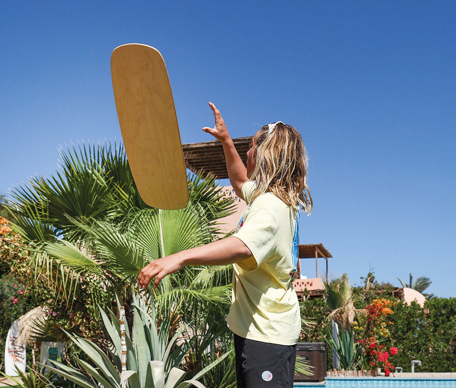 Junge Frau wirft ein F2 Balance Board Set Pill mit Korkrolle in die Luft.