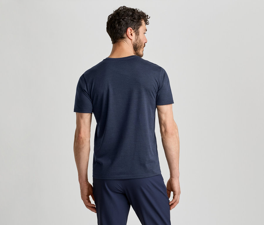 Ein Mann von hinten, der ein dunkelblaues T-Shirt und eine dunkelblaue Hose trägt und nach rechts blickt.