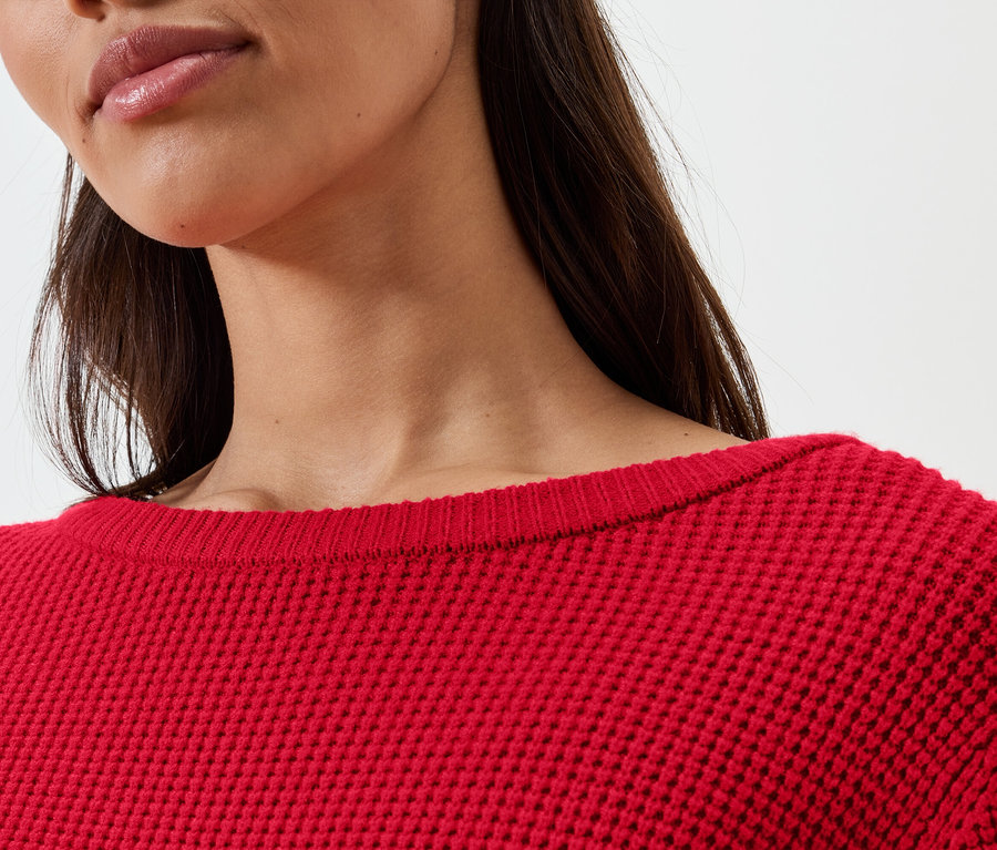 Nahaufnahme einer Frau, die einen roten Pullover trägt.