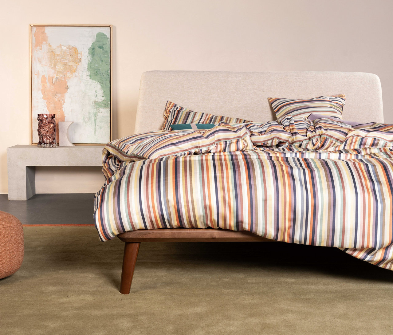 Schlafzimmer mit Essenza Satin-Bettwäsche »Donna« in Normalgröße auf einem Bett mit beigem Kopfteil und gestreifter Decke.