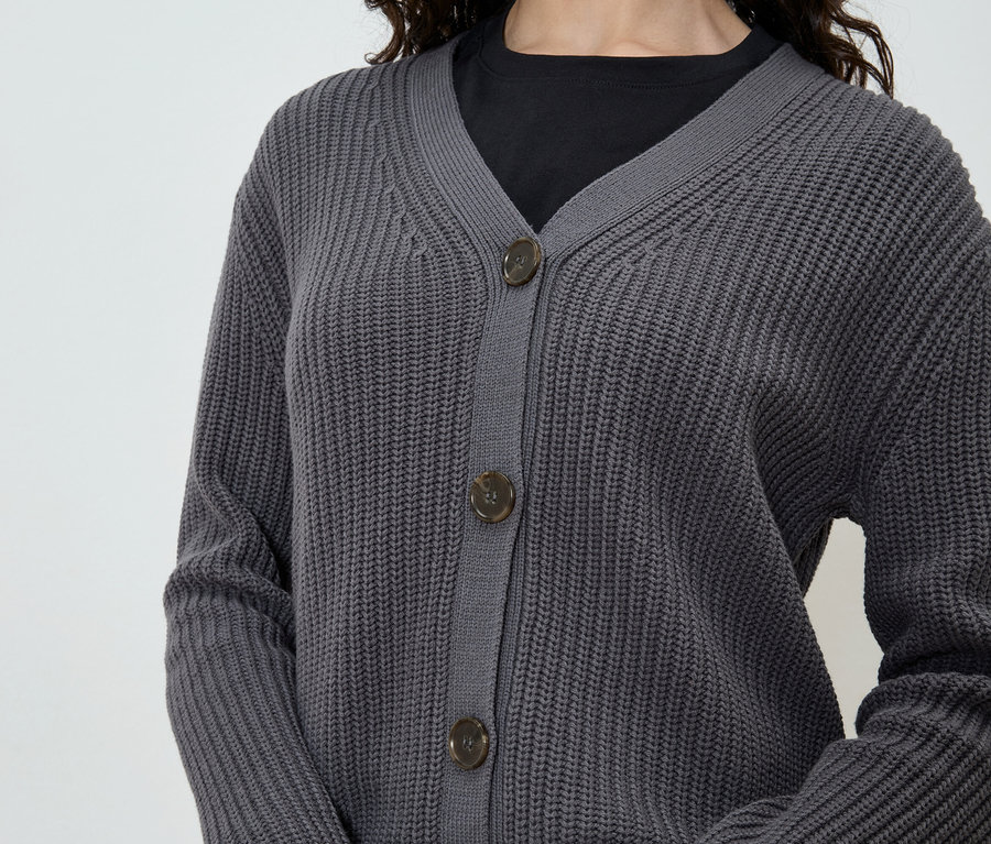 Frau trägt eine graue Strickjacke über einem schwarzen T-Shirt.