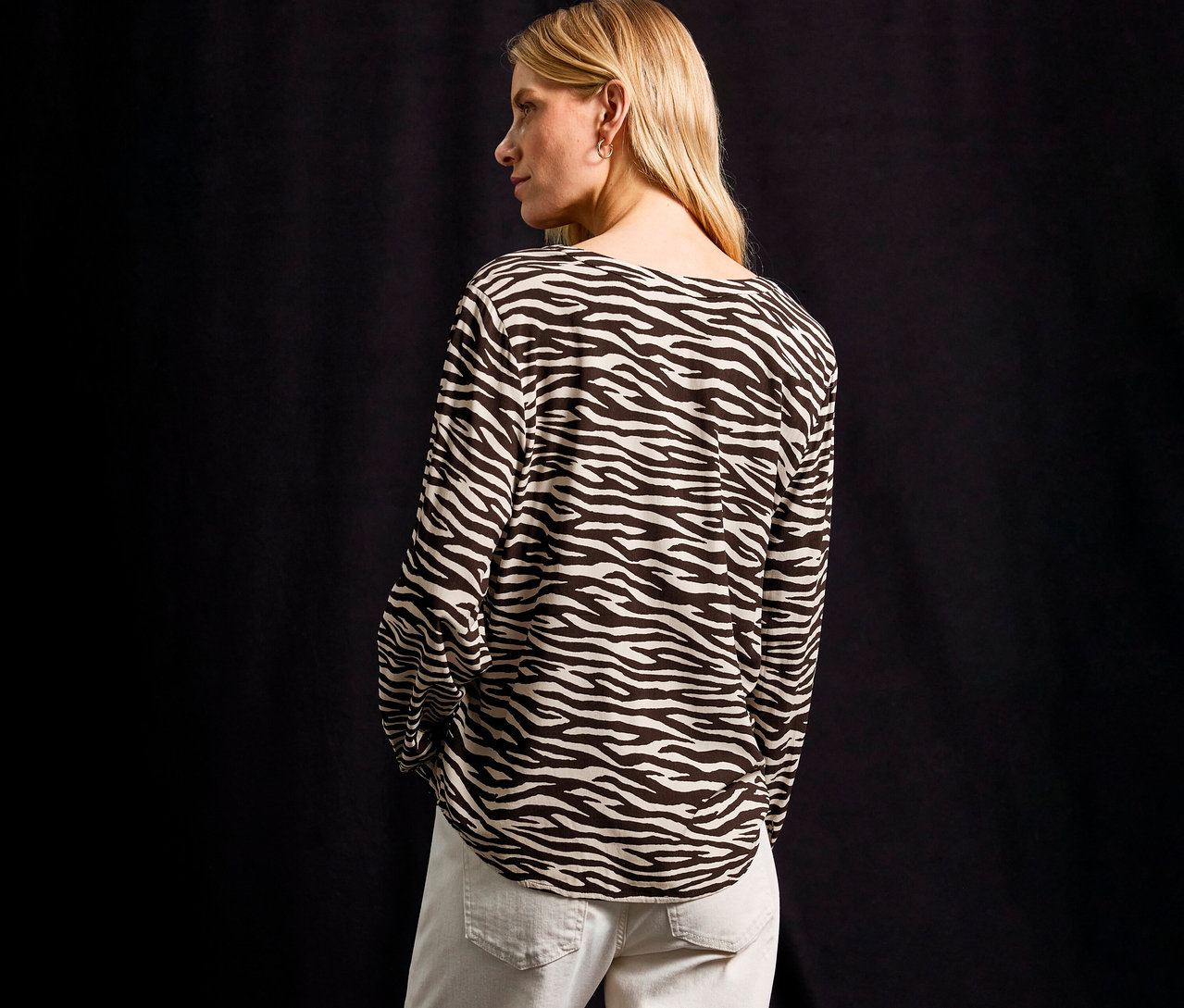 Blonde Frau trägt eine Street One Bluse mit Zebramuster und helle Jeans.