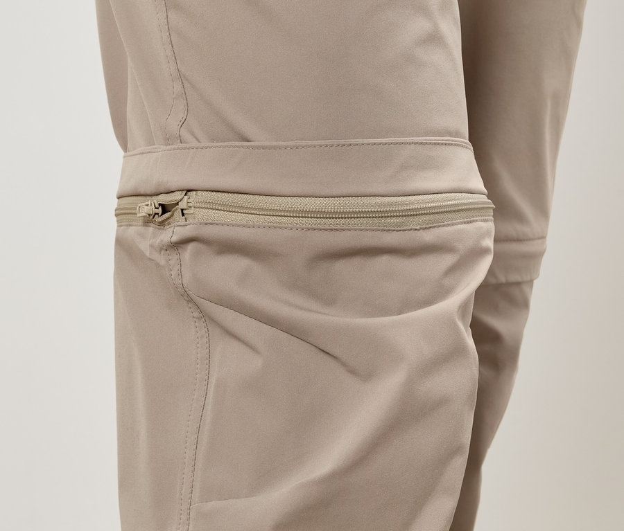Nahaufnahme einer beigen Hose mit einem Reißverschlussdetail an der Kniepartie.