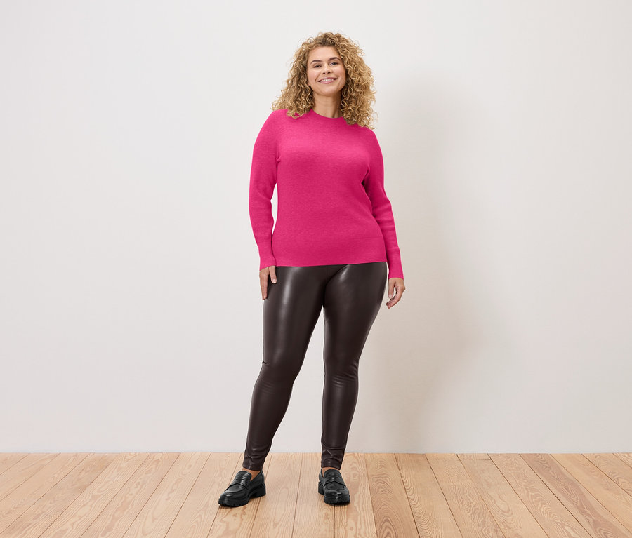 Frau trägt Leggings in Lederoptik und einen Feinstrickpullover in Fuchsia.