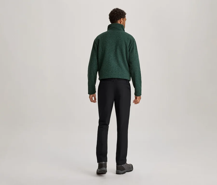 Mann von hinten, trägt eine dunkelgrüne Fleecejacke, schwarze Hose und dunkle Schuhe.