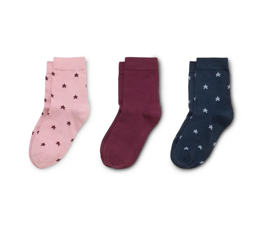Drei Paar Socken liegen nebeneinander: hellrosa mit dunkelrosa Sternen, bordeauxrot und dunkelblau mit hellblauen Sternen.