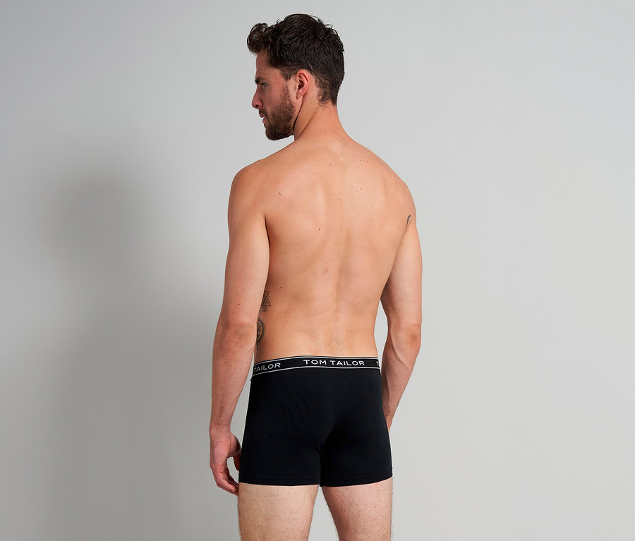 Mann von hinten, oberkörperfrei, trägt schwarze Tom Tailor Buffer Slipboxer mit Markenname am Bund.