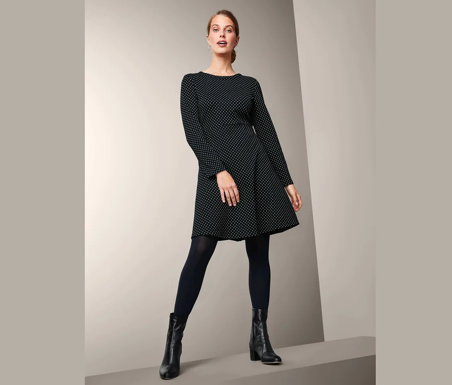 Frau posiert in einem schwarzen Jacquard-Kleid.