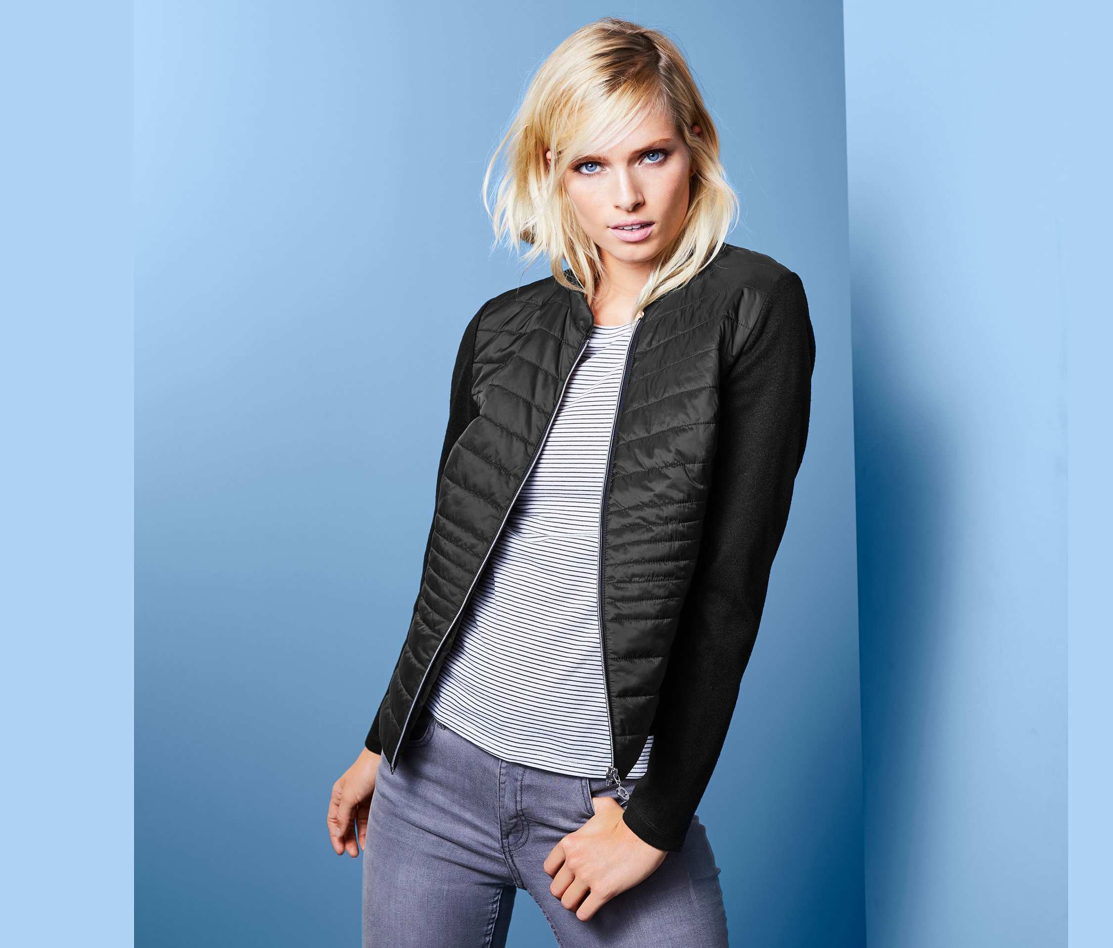 Blonde Frau posiert in Jacke im Materialmix.