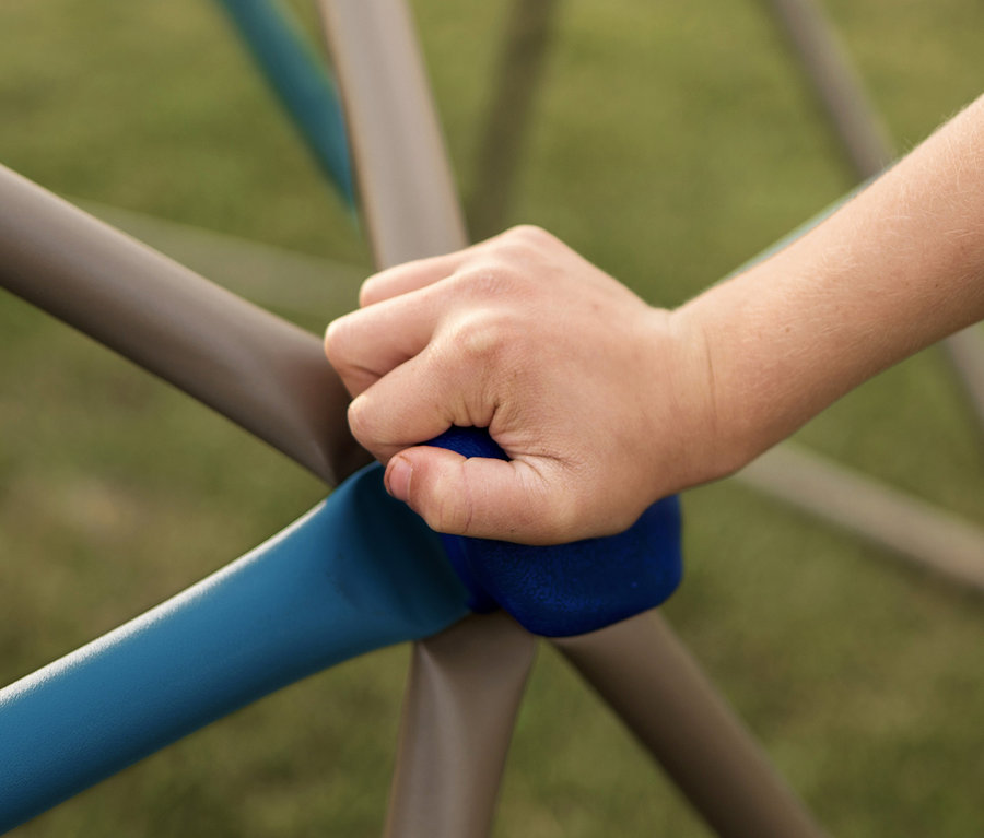 Die Hand eines Kindes hält einen blauen Griff an einem kleinen LIFETIME-Klettergerüst »Geodome«.