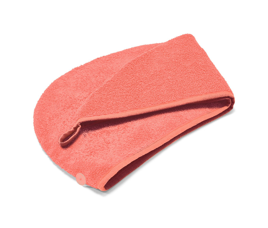 Ein korallefarbenes Turban-Handtuch liegt auf einem weißen Hintergrund.