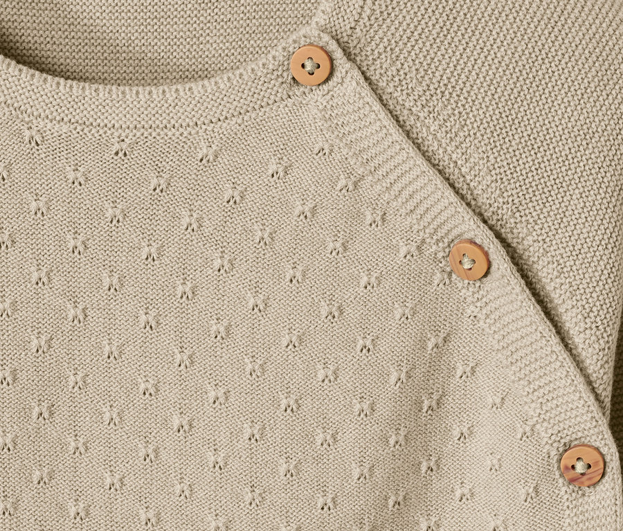 Detailaufnahme einer Babystrickjacke mit Knöpfen.