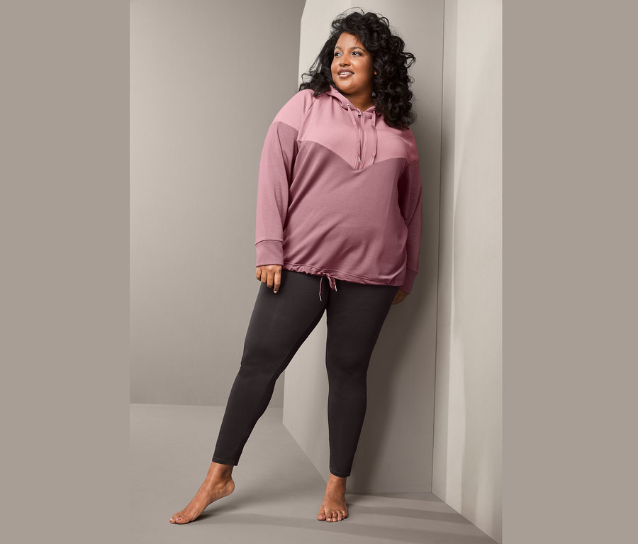 Frau posiert in Sweatpullover und Sporttight.