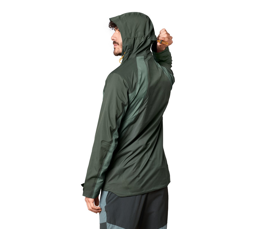 Mann justiert die Zugschnur seiner grünen Outdoorjacke mit Kapuze.