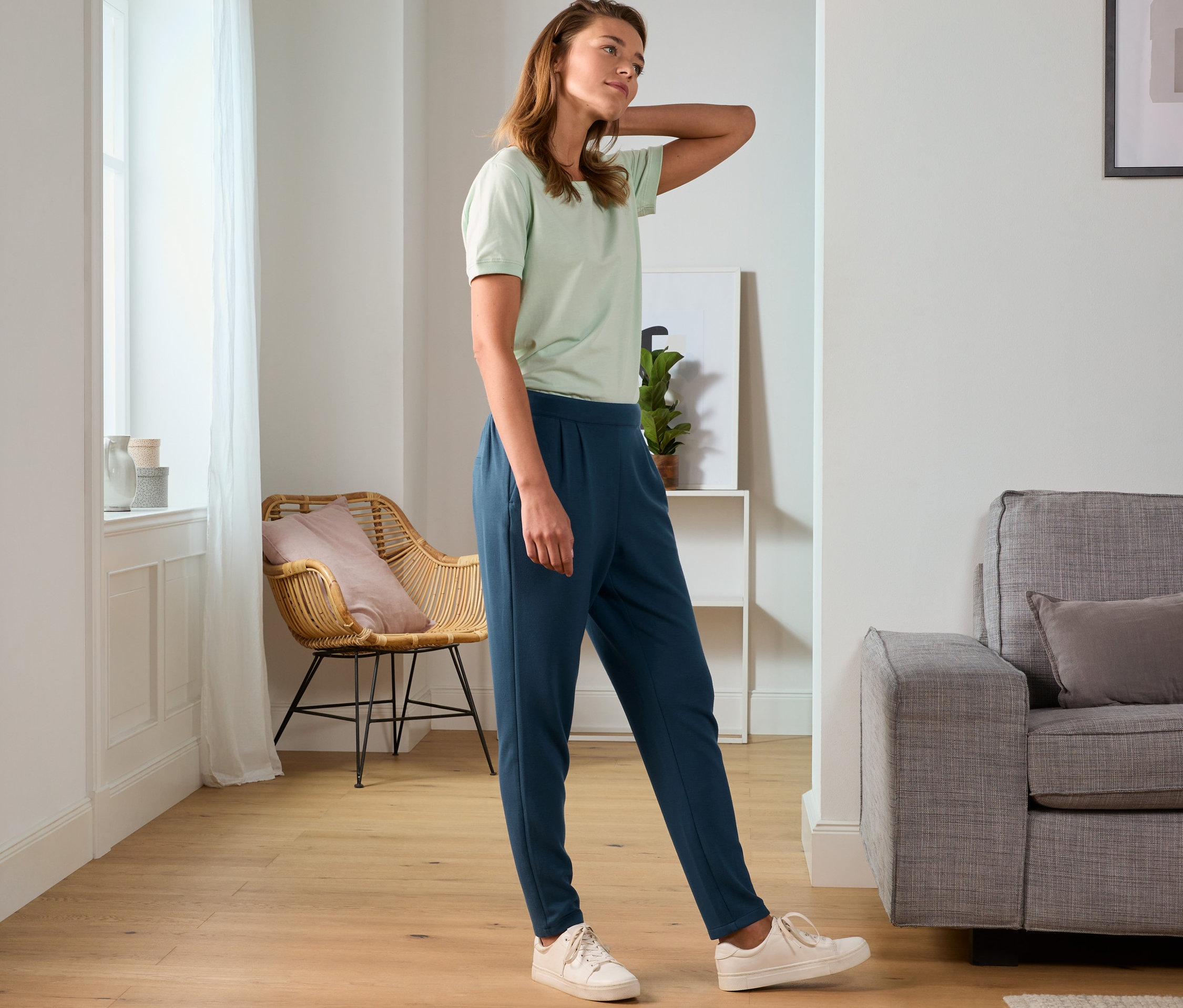 Frau posiert in grünem T-Shirt und Sweathose.