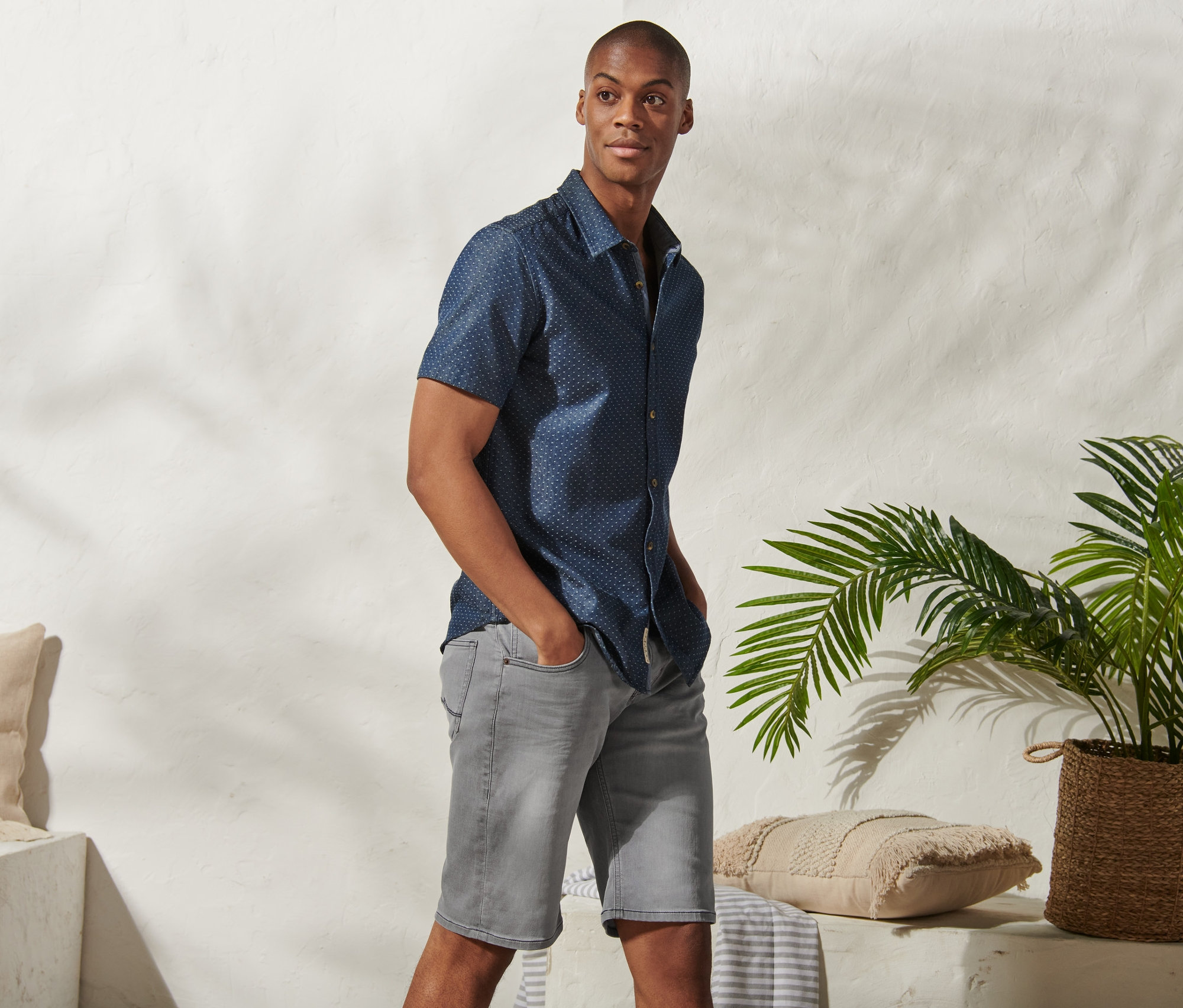 Ein Mann posiert in grauen Jeans-Shorts »Mustang« und einem blauen Kurzarmhemd.