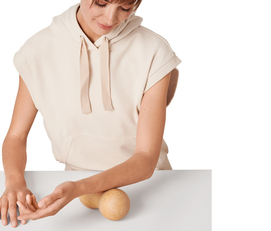 Frau verwendet Duo-Massageball aus Holz auf ihrem Unterarm.