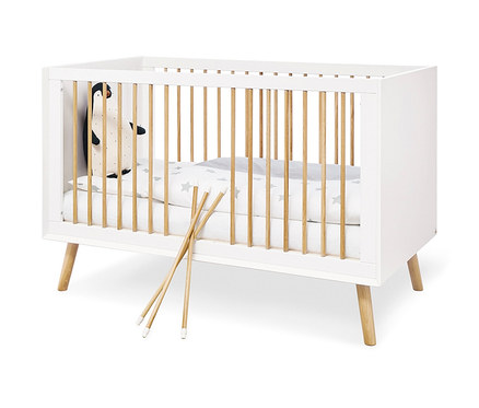 Weißes Pinolino Babybett »Edge« mit Holzstäben und einem Plüschpinguin darin.