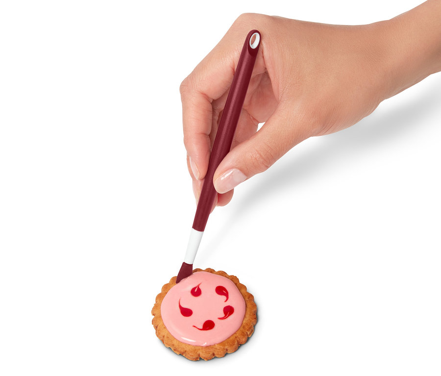 Eine Hand verziert einen Keks mit Zuckerguss aus einem Royal-Icing-Set.