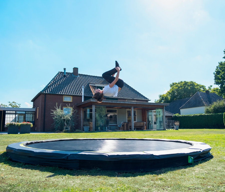 Eine junge Frau macht einen Salto auf einem EXIT Bodentrampolin »Silhouette sports«, Ø ca. 427 cm.
