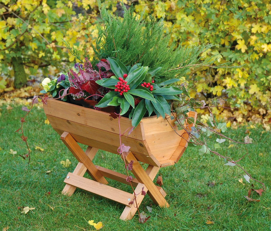 Blumenfass aus Holz mit Pflanzen auf Rasen.