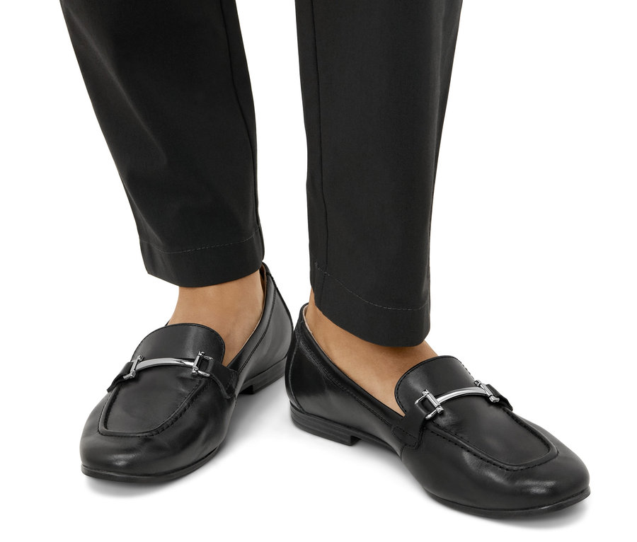 Füße in schwarzen Leder-Loafern.
