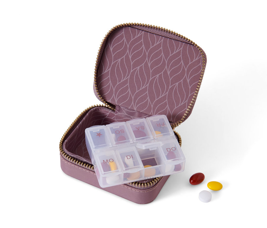 Offene lila Pillendose mit Hülle und Tabletten drin und daneben.