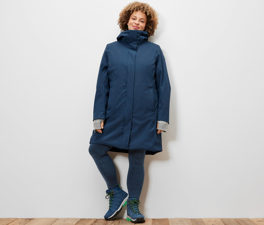 Frau posiert in Sporttights und 3-in-1-Funktionsmantel mit Weste.