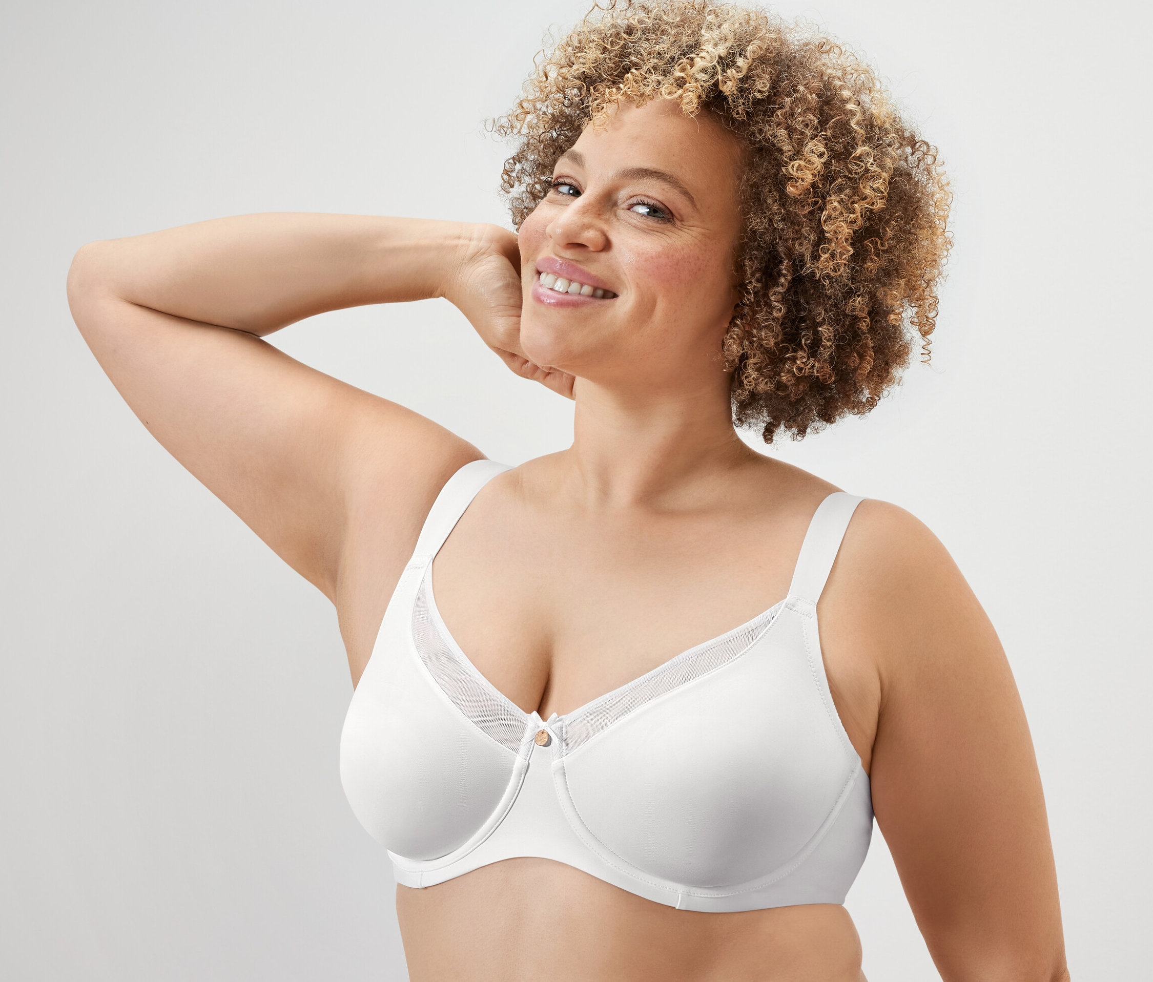 Lächelnde Frau posiert in weißem Minimizer-BH.