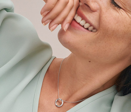 Lächelnde Frau mit Doppel-Creolen, 925 Silber rhodiniert, mit Zirkonia und Kette Circle, 925 Silber rhodiniert, mit Zirkonia.