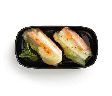 Zwei Sommerrollen in einer schwarzen Lunch-Box-Set mit Besteck und einem Minzblatt.