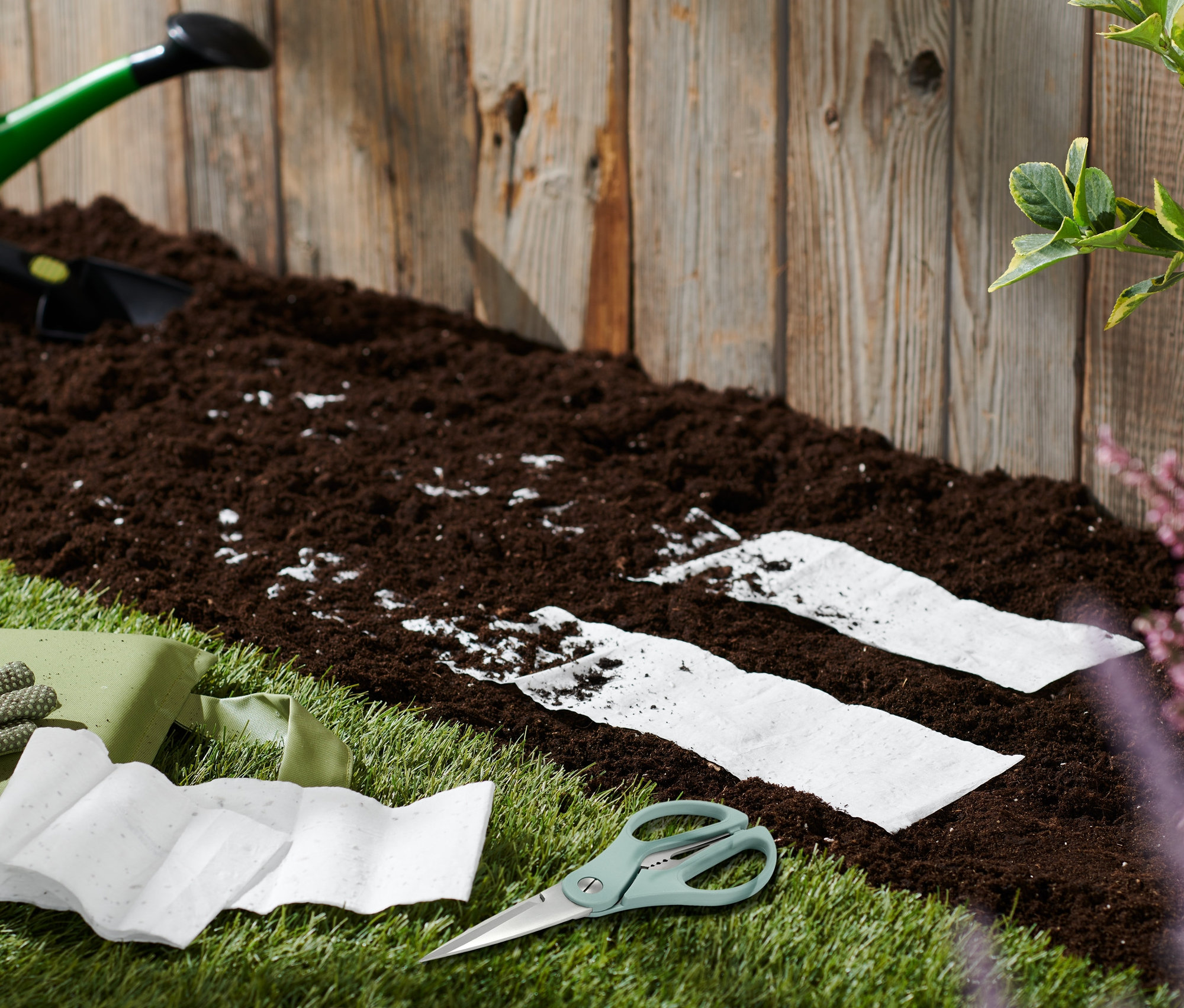 Gartengeräte und Saatteppiche Bienenwiese auf Rasen neben Erde.