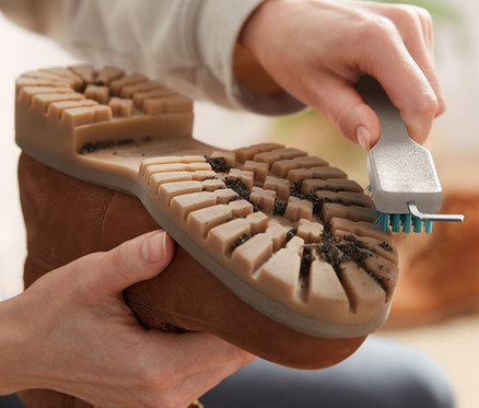 Person reinigt mit einer Grobschmutz-Schuhsohlenreinigungsbürste einen braunen Stiefel.