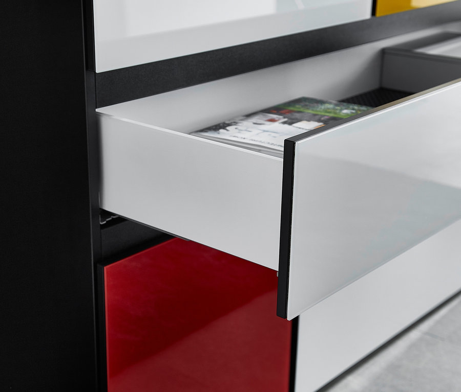 Detailansicht eines schwarz-weißen Highboards »Ideeus« mit roten Akzenten und einer offenen Schublade.