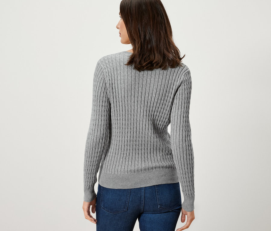 Frau trägt einen grauen Zopfstrickpullover.