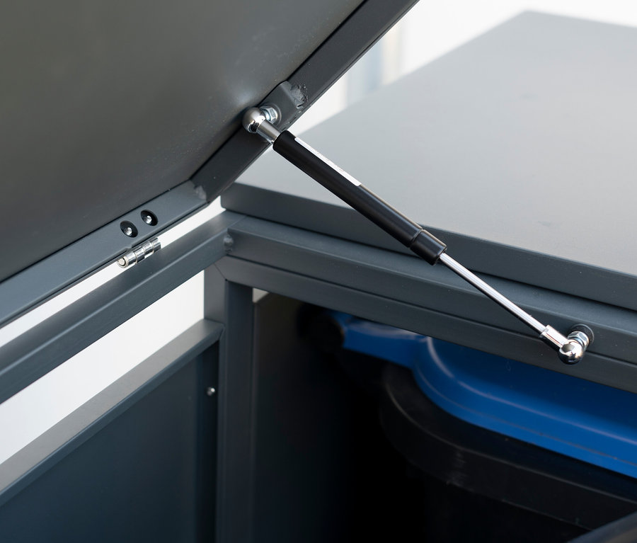 Detail einer Stahl-Mülltonnenbox mit geöffnetem Deckel und blauer Mülltonne im Inneren.